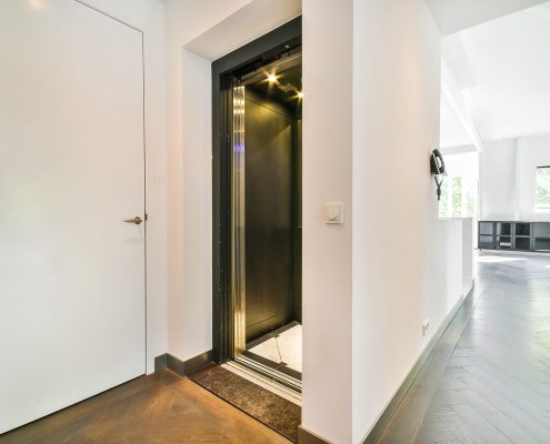 Residential home elevator with open black door in modern hallway