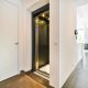 Residential home elevator with open black door in modern hallway