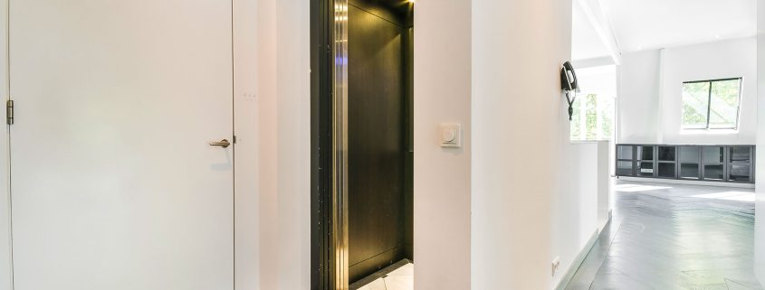Residential home elevator with open black door in modern hallway